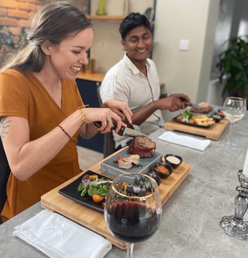 people dining on a sizzling steak on a stone hot stone cooking rock set by black rock grill