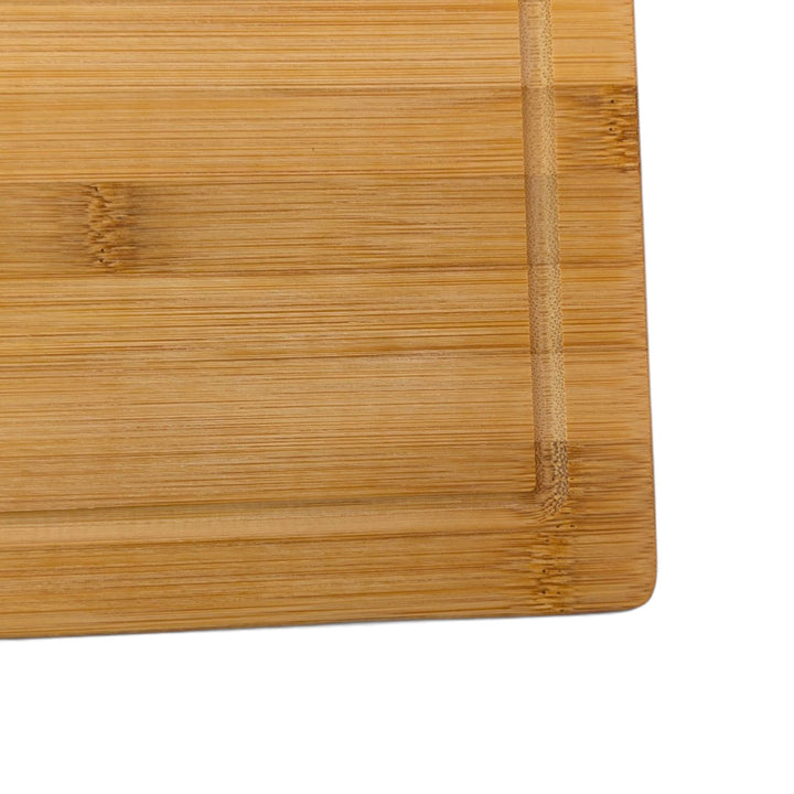 Close-up corner view of a bamboo chopping board featuring a deep perimeter juice groove and clean edge detail.