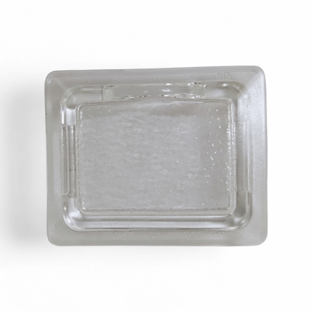 A clear, rectangular Effeuno Lamp Shade Glass- Flat Fitting by Effeuno is shown from above on a white background, filled with coarse white salt.