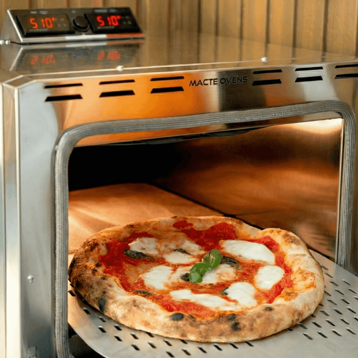 Close-up of a freshly baked pizza being removed from the Macte Nettuno Advanced pizza oven.