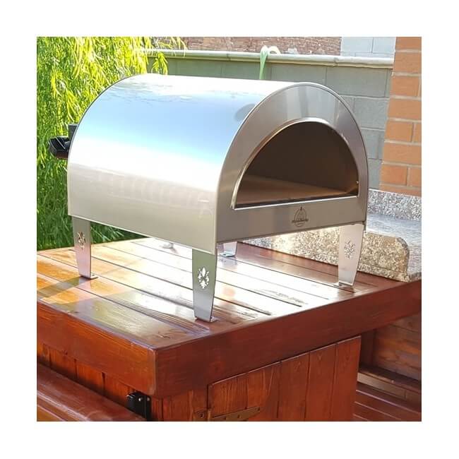Bright silver pizza party ardore outdoor pizza oven on a wooden platform with a garden background