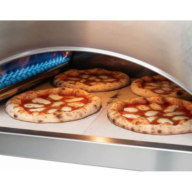A close-up view of four pizzas cooking simultaneously inside the Pizza Party Ispirazione outdoor gas pizza oven.