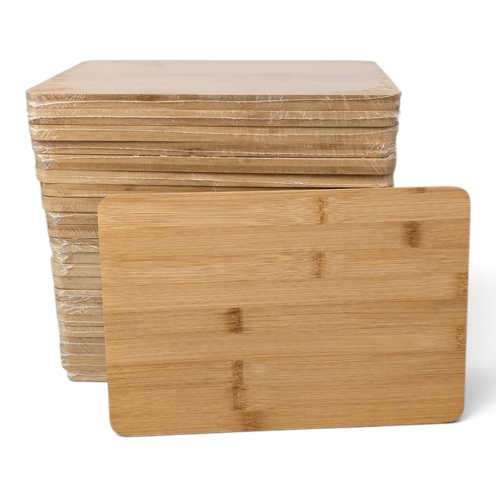 A stack of Black Rock Grill Bamboo Serving Steak Boards (30x20x1.2cm), featuring smooth finishes and rounded corners, with one board standing upright in front of the stack—ideal for custom laser engraving.