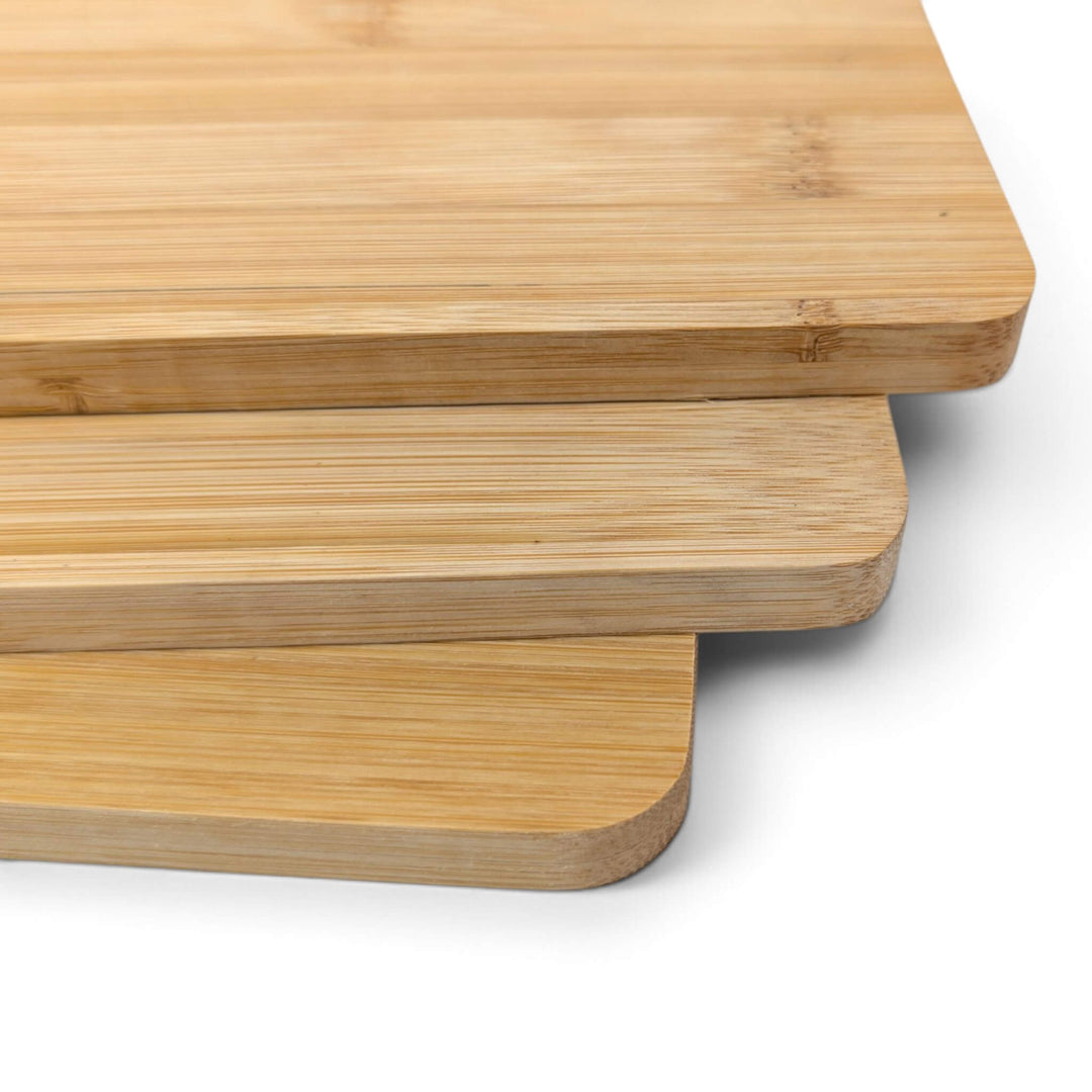 Three stacked Black Rock Grill Bamboo Serving Steak Boards (30x20x1.2cm) with rounded corners are displayed against a white background. The boards’ natural grain patterns and smooth edges are clearly visible, making them ideal for serving steak. Perfect for custom laser engraving, these versatile boards add both function and style to any kitchen or dining occasion.