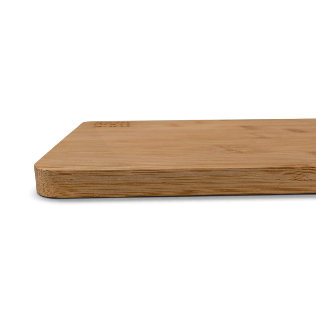 A close-up side view of the Black Rock Grill Bamboo Serving Steak Board (30x20x1.2cm) placed on a white surface, featuring smooth, rounded edges and a flat surface—ideal for use as bamboo serving boards or for custom laser engraving to create a personalized touch.