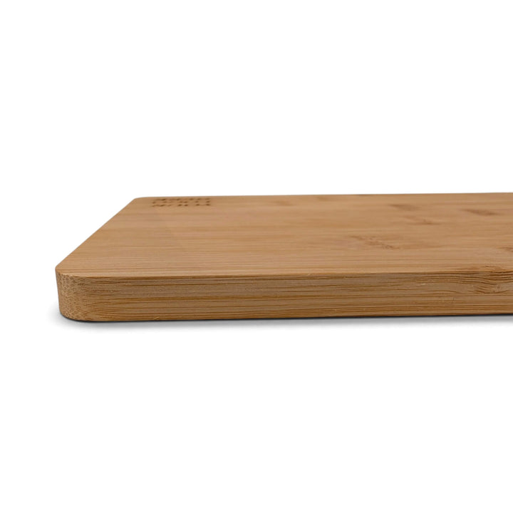 A close-up side view of the Black Rock Grill Bamboo Serving Steak Board (30x20x1.2cm) placed on a white surface, featuring smooth, rounded edges and a flat surface—ideal for use as bamboo serving boards or for custom laser engraving to create a personalized touch.
