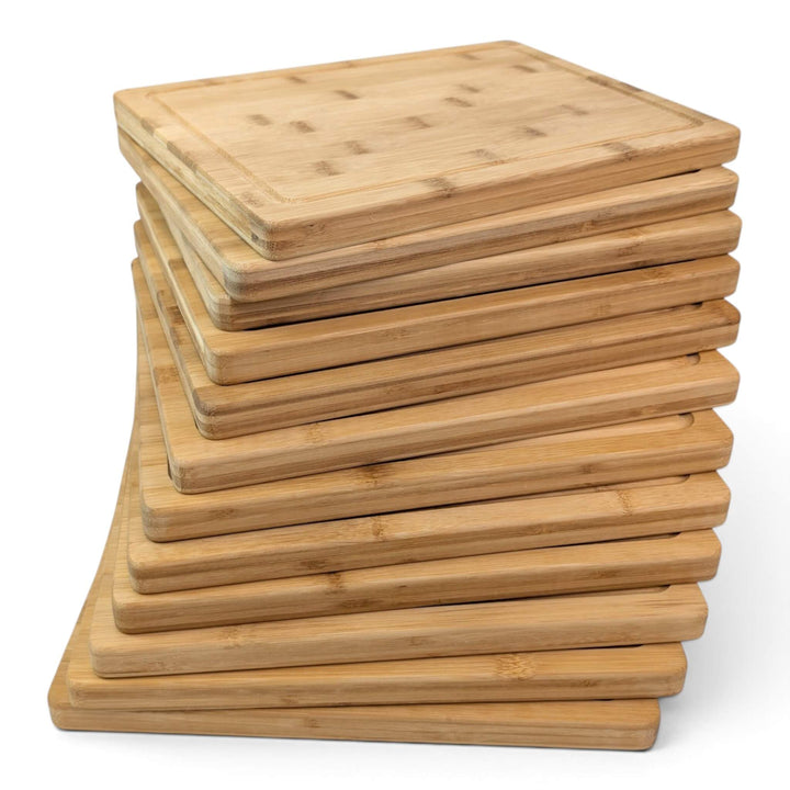 A stack of twelve rectangular bamboo chopping or serving boards with rounded corners, shown on a clean white background.