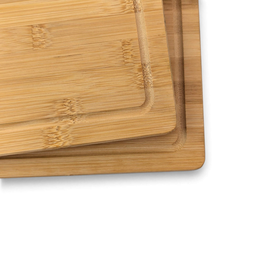 Two rectangular bamboo cutting boards with raised edges, stacked slightly offset on a plain white background.