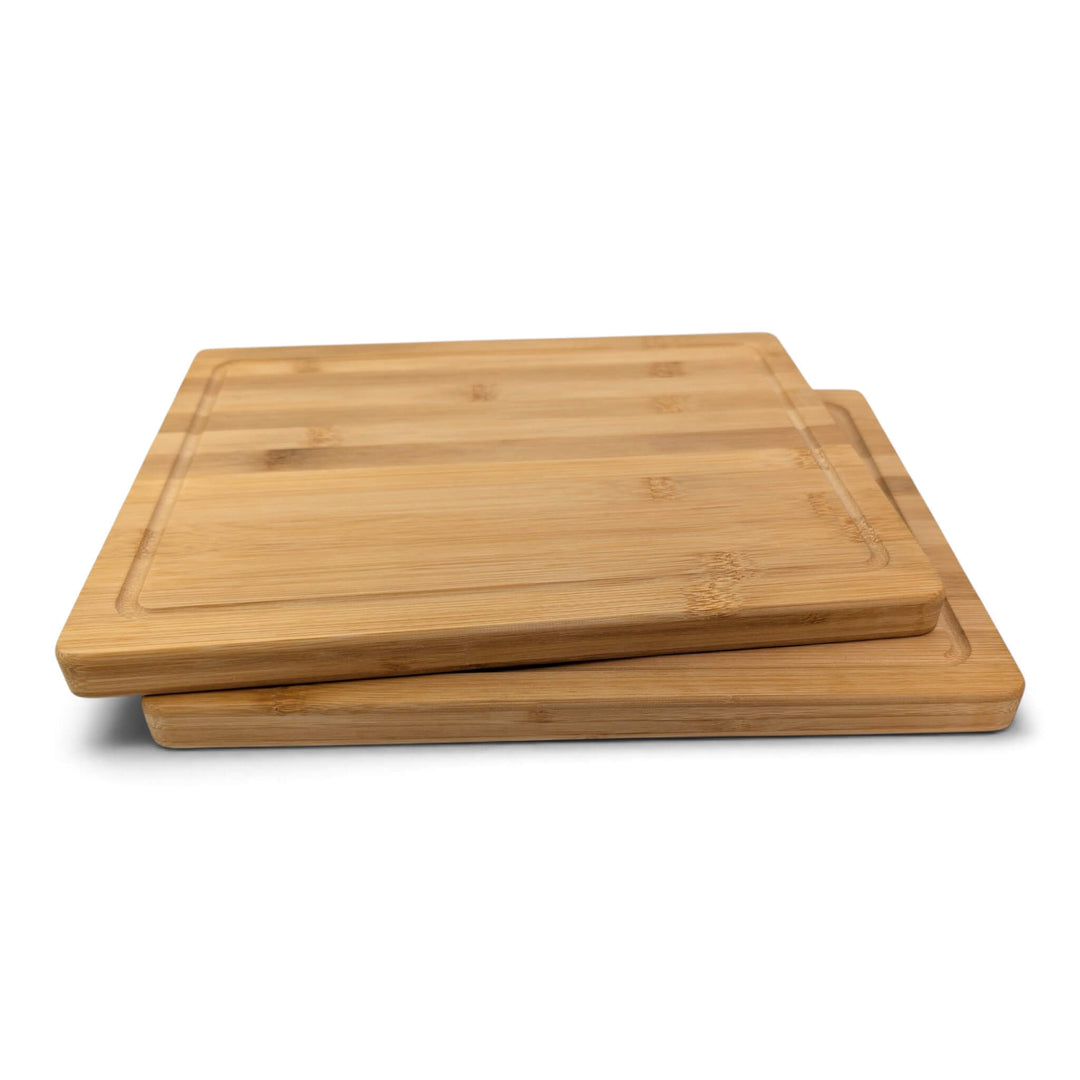 Side view of two rectangular bamboo chopping boards stacked slightly offset on a clean white background.