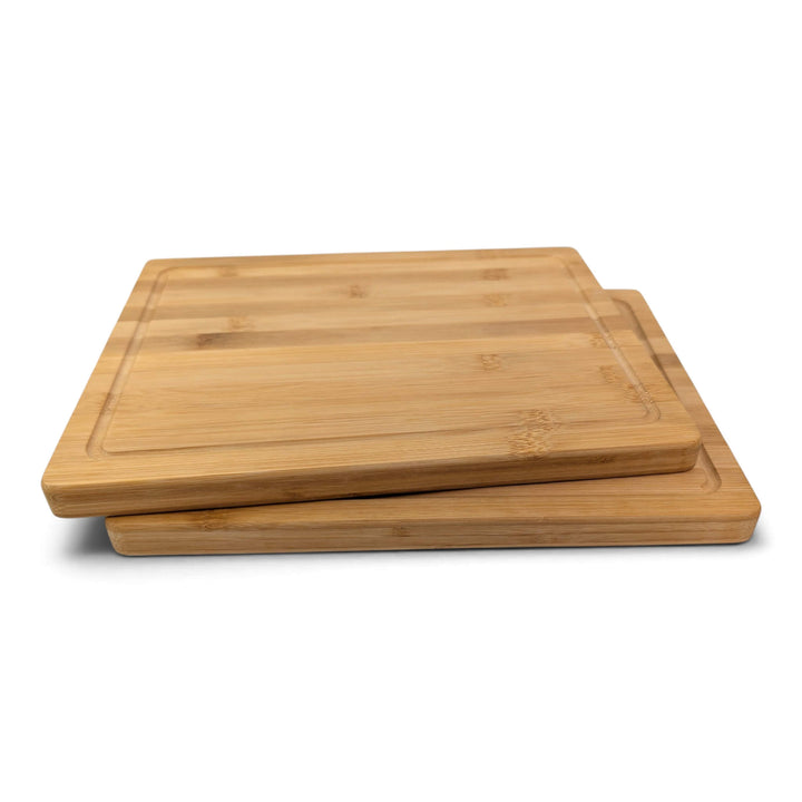 Side view of two rectangular bamboo chopping boards stacked slightly offset on a clean white background.