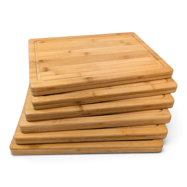 A stack of six rectangular bamboo serving boards, stacked and flayed out shown on a clean white background.