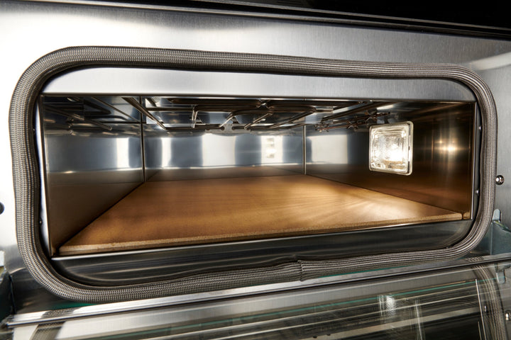 Interior view of the Black Rock Grill Effeuno P134H 509 Manual Pizza Oven with a stone surface, stainless steel interior, and light—perfect for baking authentic Neapolitan-style pizza.