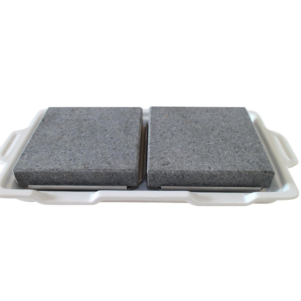 Two gray stone slabs sit on a smooth, handled white porcelain tray, mimicking double rock platters. The slabs have a rough texture and are evenly spaced with a small gap between them, adding elegance to this GP-3 setup by Black Rock Grill.