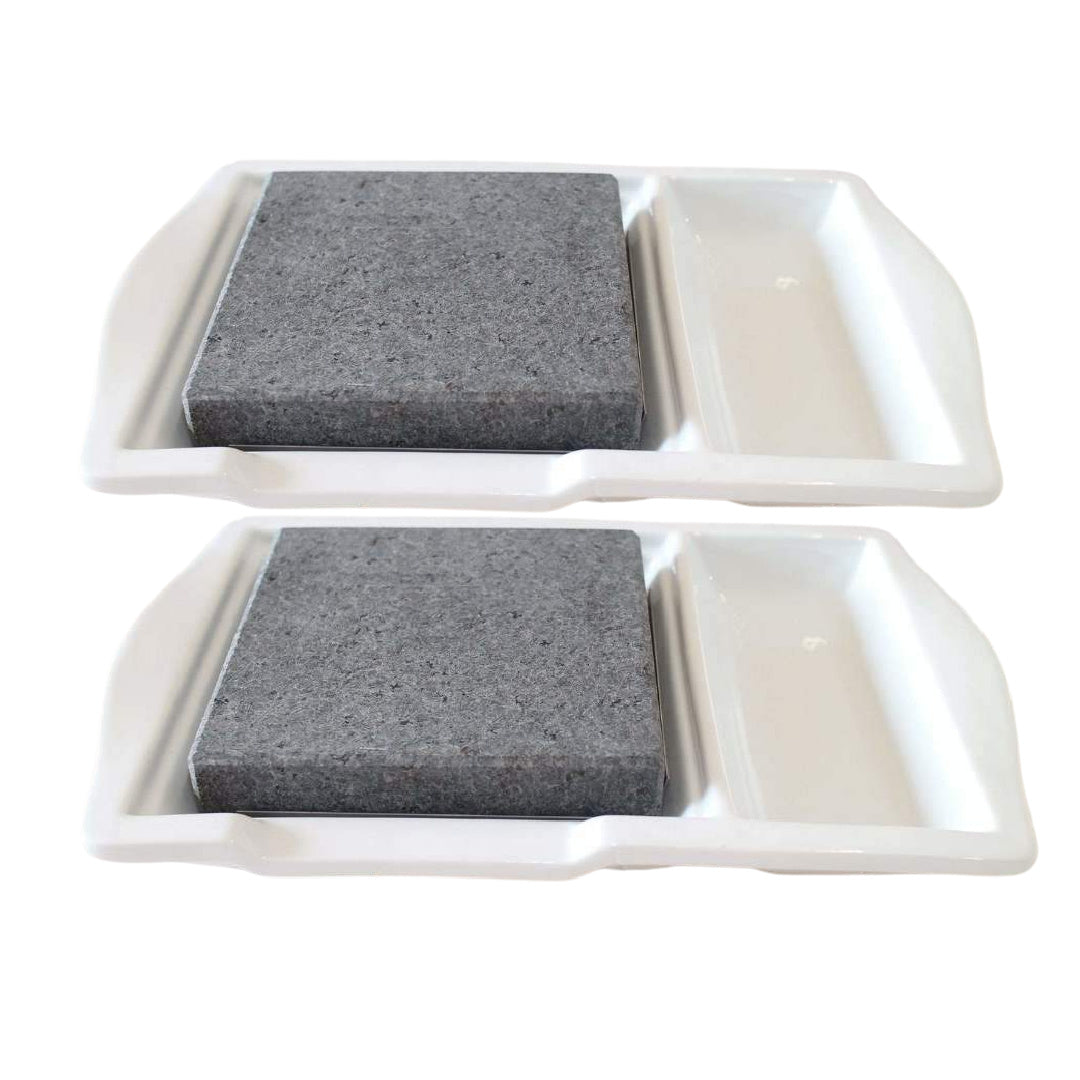 The Black Rock Grill Steak Stone Plate Set, a 2 pack, features a sleek modern design with two rectangular trays. Each white tray includes a gray stone block and an adjacent side area for your choice, perfect for healthy dining against a minimalist white backdrop.