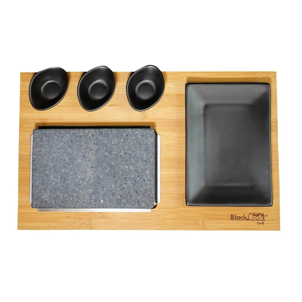 The Black Rock Grill GP-7 Bamboo Boards for Steak Stone Cooking Set include a sustainable bamboo tray, rectangular stone slab, large black plate, and four small dipping bowls—perfect for stylish steak stone dining.